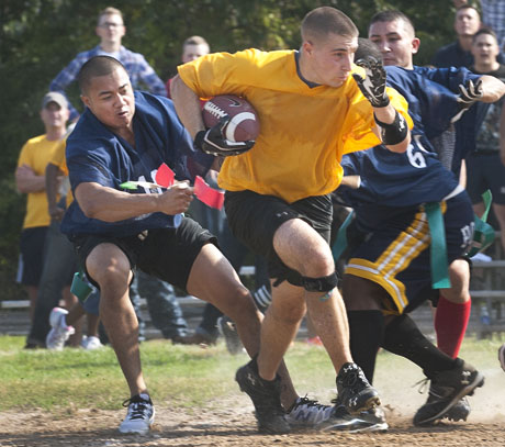 DINFOS broadcast instructor, Marine Staff Sgt. Joseph DiGirolamo, breaks away from a defender during the Defense Information School's annual Toilet Bowl faculty football game at Mullins Field. Despite DiGirolamo's efforts, The Air Force-Army group broke a three-year losing streak with their 13-7 victory over the Marine-Navy-Coast Guard gridders. (Photo by Sarah Pastrana courtesy of Fort Meade Public Affairs Office)