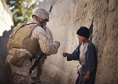 New Gesture in an Old Country - LCpl. Dominic Evola, a 29-year-old rifleman with Jump Platoon, H&S Company, 3rd Battalion, 3rd Marine Regiment, from Medford, N.J., greets an Afghan boy by “pounding fists” while traveling to a local residence for a shura Nov. 22. The photo appeared in a recent issue of Marine Corps Times and was taken by CC Cpl. Reece Lodder who was named Outstanding New Writer in last year's Merit Awards competition. Lodder is with Regimental Combat Team-5, 1st Marine Division